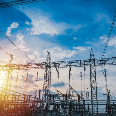 Sunset behind substation towers with blue sky.
