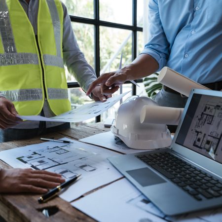 Close up of hands working and brainstorming on paperworks and floor plan drawings about design architectural and engineering for houses and buildings.